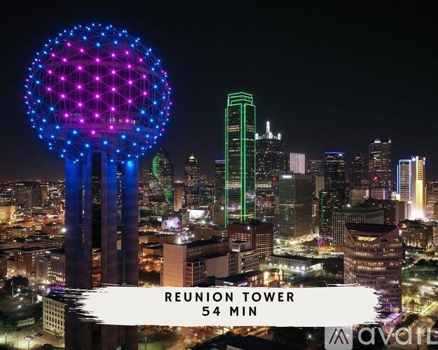 A cityscape at night with a Reunion Tower and a building with green lights.