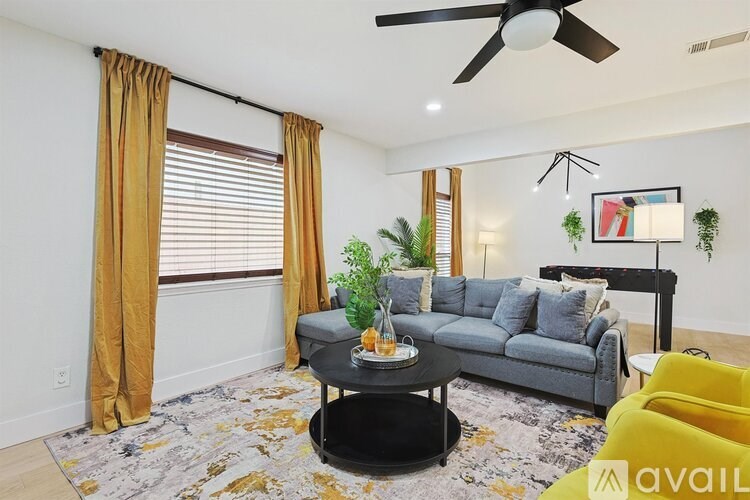 A living room with a grey couch, a black coffee table, and a ceiling fan.