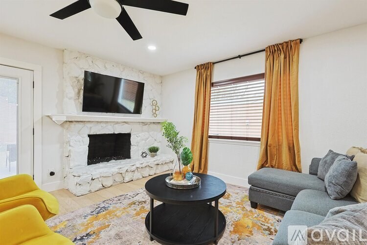 A living room with a fireplace, a TV, a plant, and a couch.