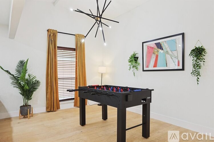 A pool table is in the middle of a room with a plant on the side.