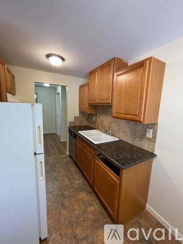 A kitchen with wooden cabinets and a white fridge.