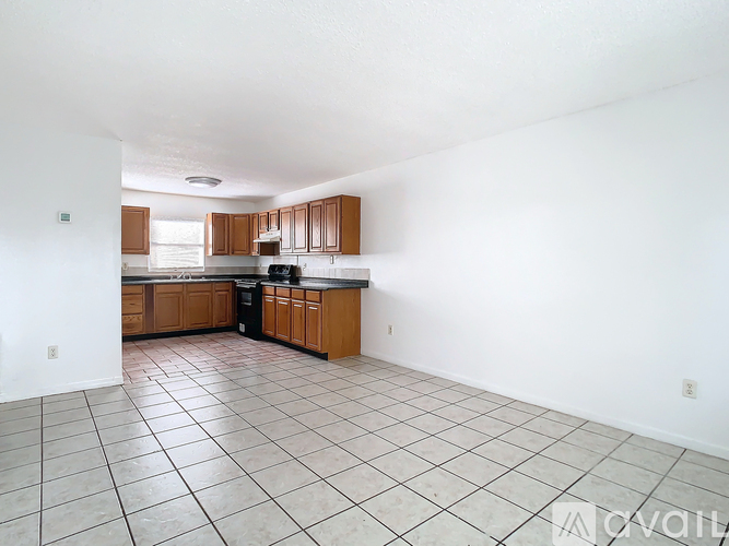 A kitchen with white walls and brown cabinets.