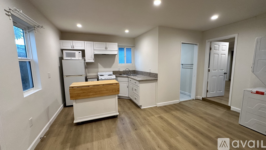 A kitchen with white cabinets and a wooden island.