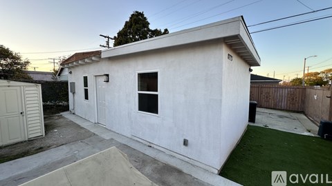 A white house with a brown fence and a small garden.