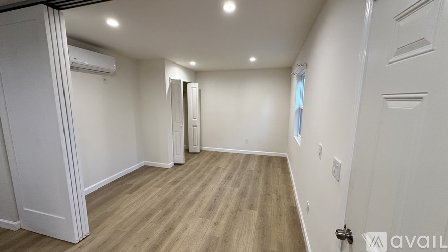 A spacious room with wooden flooring and white walls.