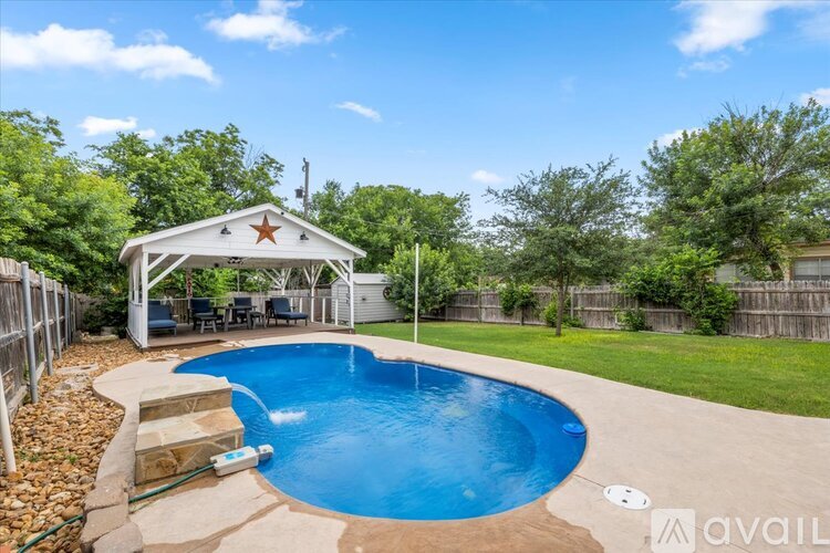 A pool with a waterfall and a gazebo in the backyard.