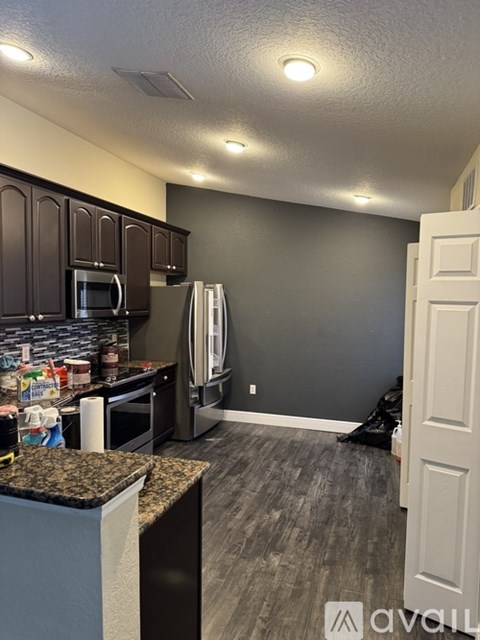 A kitchen with a granite counter top and dark brown cabinets.