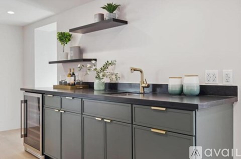 A kitchen with grey cabinets and a black countertop.