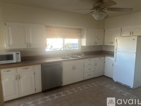 A kitchen with white cabinets and a white refrigerator.