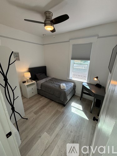 A bedroom with a bed, nightstand, and a ceiling fan.