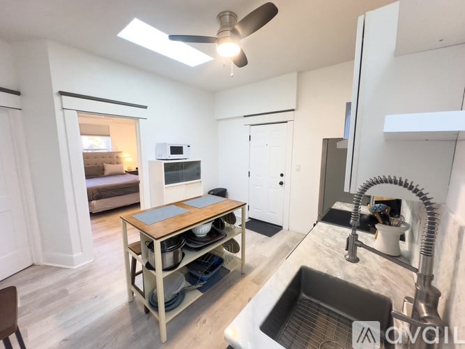 A kitchen with a sink, a table, and a ceiling fan.