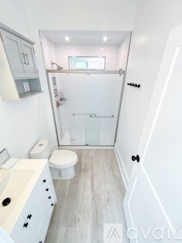 A white bathroom with a toilet, sink, and shower.