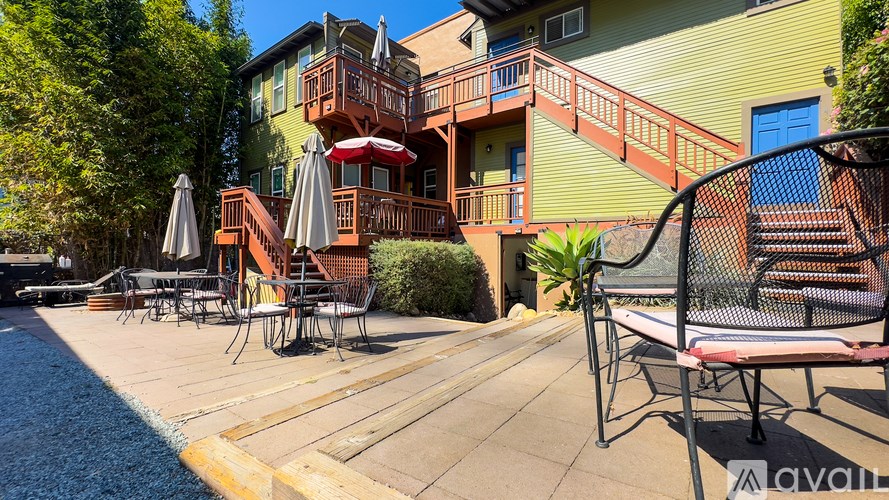 A patio with chairs and a table is in front of a multi-story building.