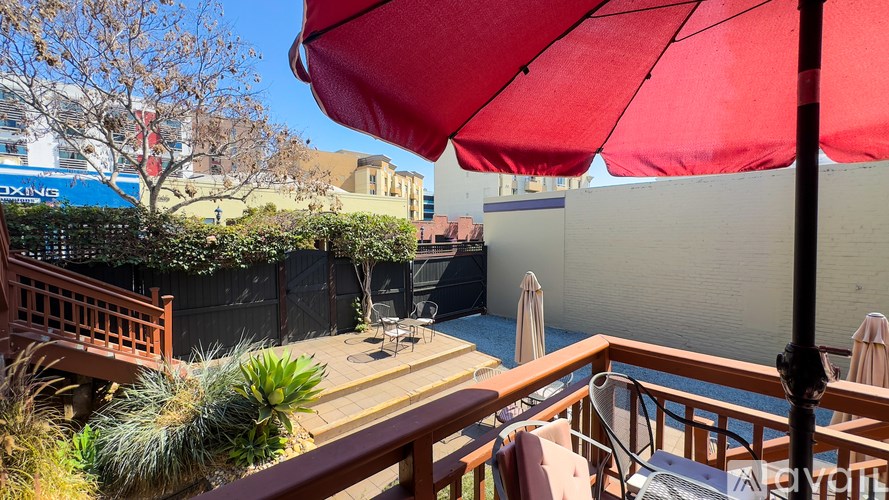 A red umbrella is on a balcony overlooking a pool.