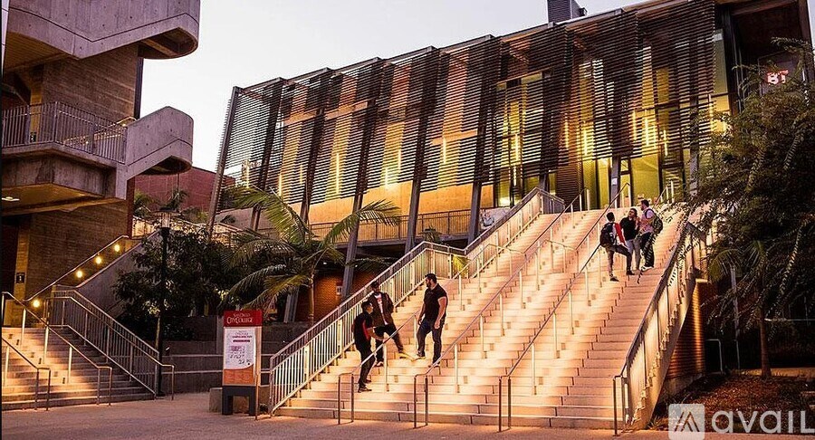 A group of people are walking up a flight of stairs outside a building with a glass facade.