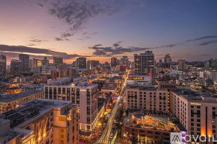 A cityscape at dusk with buildings illuminated and streets bustling with activity.