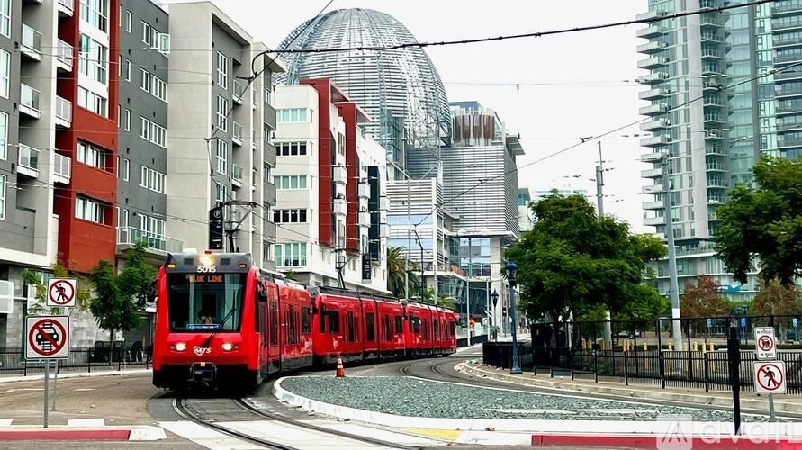 A red train is on the tracks in the city.