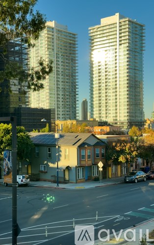 A street view with two tall buildings in the background and a car driving on the road.
