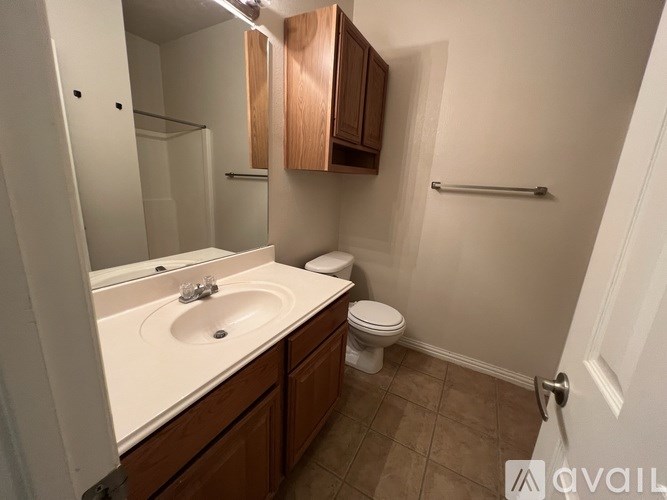A bathroom with a toilet, sink, and mirror.
