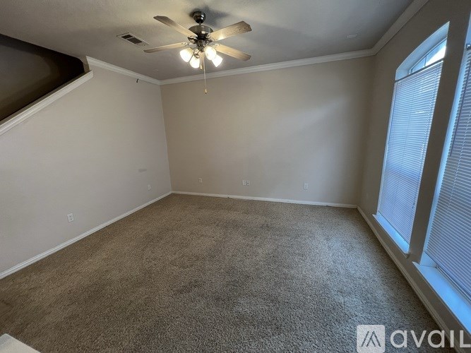 A room with a carpeted floor and a ceiling fan.