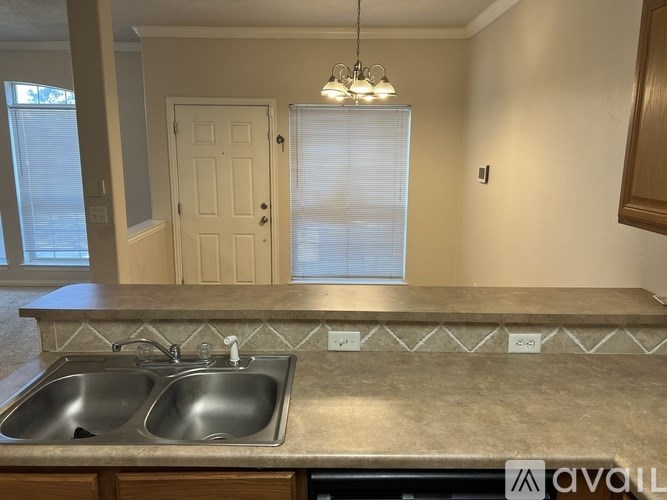 A kitchen with a double sink and a window with blinds.