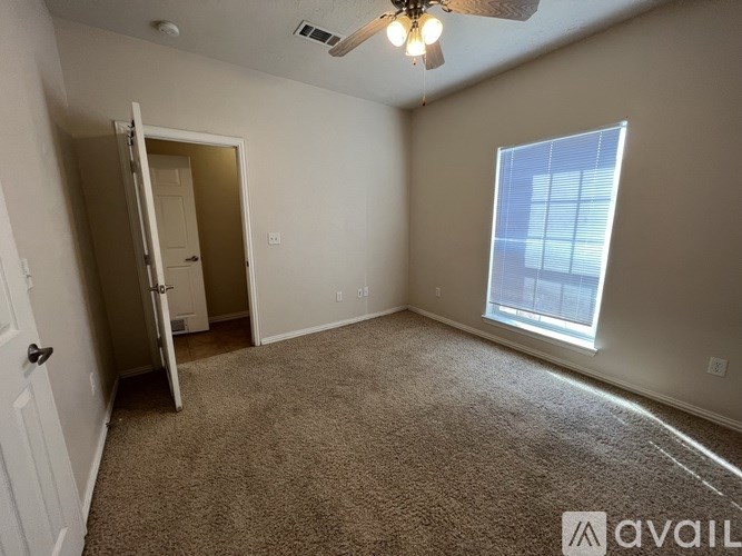 A room with a carpeted floor, a ceiling fan, and a window with blinds.