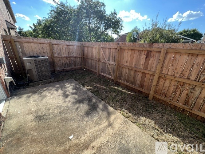 A backyard with a wooden fence and a concrete patio.