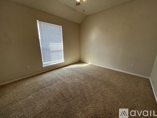 A room with a carpeted floor and a window with blinds.