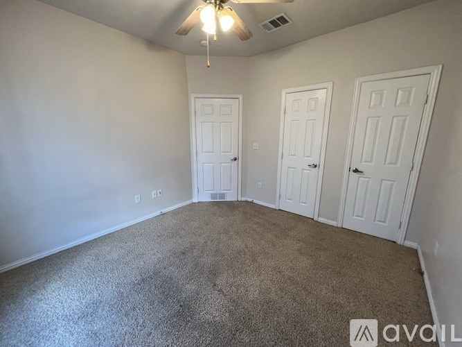 A room with a carpeted floor and three doors.