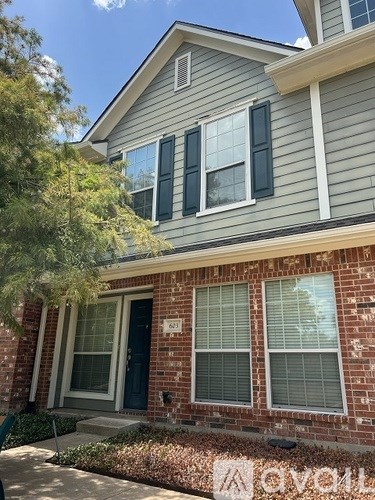 A house with a grey siding and a brick wall with a window and a door.