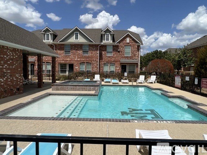 A pool with a brick house in the background.