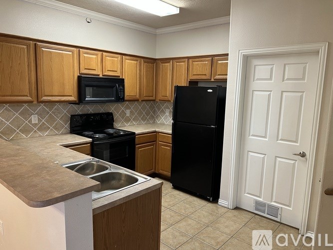 A kitchen with wooden cabinets and black appliances.
