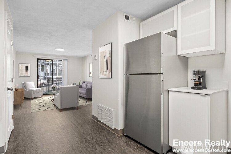 A kitchen area with a refrigerator, a sink, and a coffee maker.