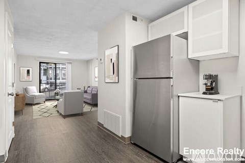 A kitchen area with a refrigerator, a sink, and a coffee maker.