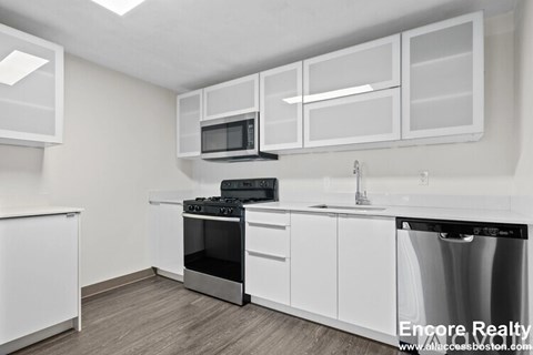 A kitchen with white cabinets and appliances.
