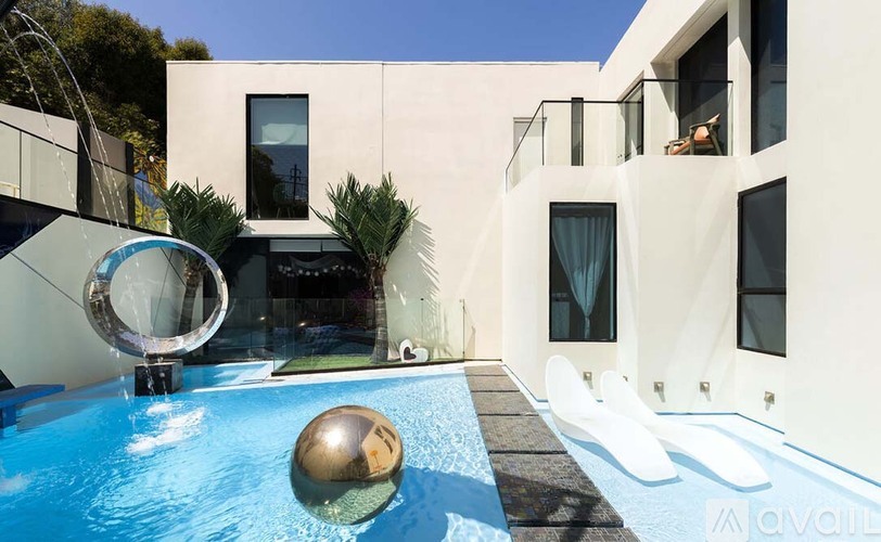 A modern house with a pool and a sphere in the middle of it.