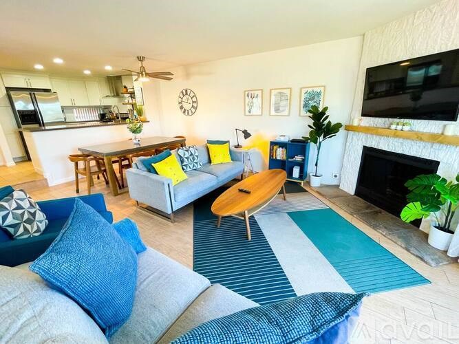 A living room with a grey couch and a blue and white rug.