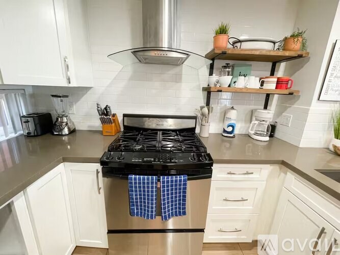 A kitchen with a stove top oven and white cabinets.