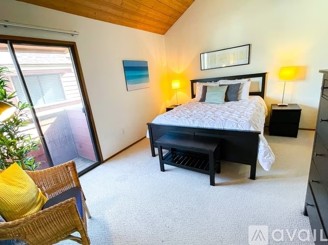 A bedroom with a bed, nightstand, and chair.