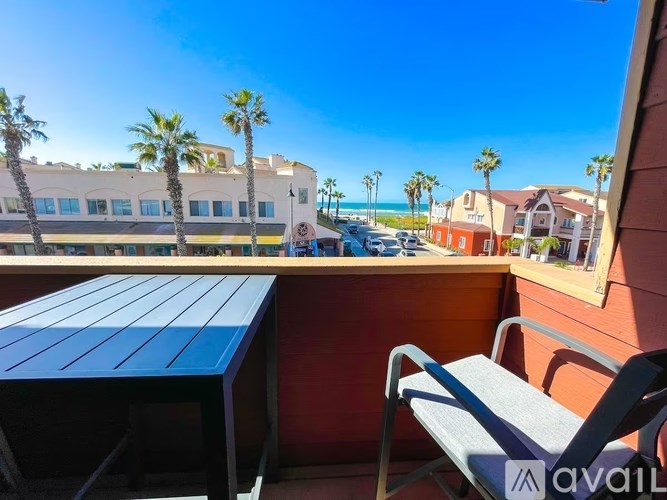 A blue table and chair set on a balcony with palm trees in the background.