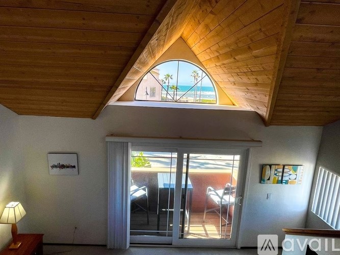 A room with a wooden ceiling and a view of the beach through a window.