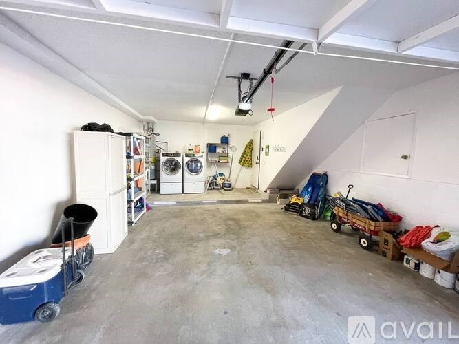 A large, empty garage with a blue cart and a white refrigerator.