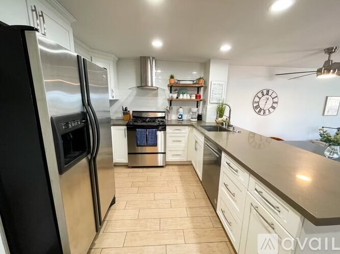 A modern kitchen with a black refrigerator and wooden flooring.