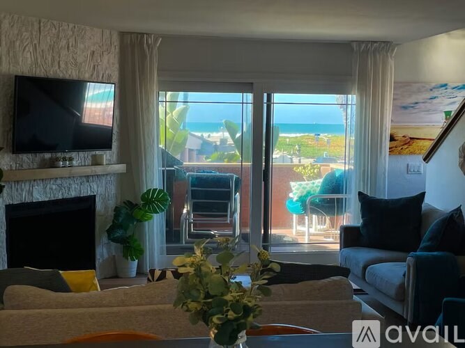 A living room with a fireplace and a view of the ocean.