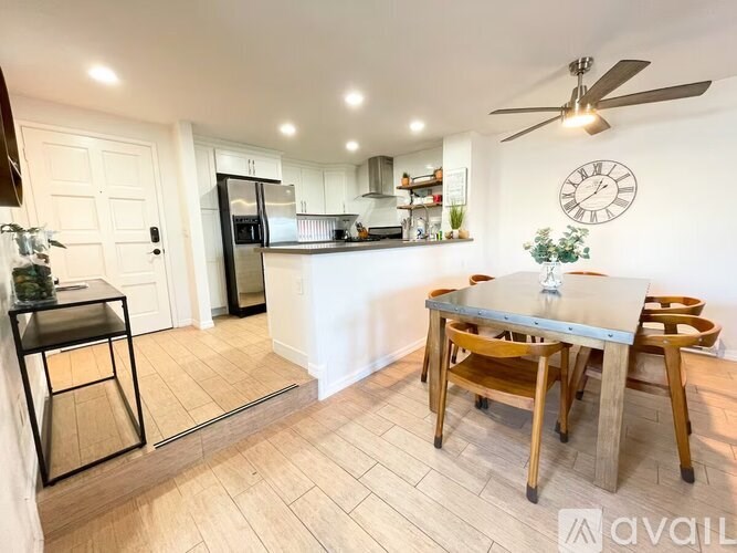 A kitchen with a table and chairs in the foreground and a refrigerator in the background.
