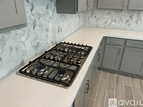 A modern kitchen with a white countertop and a stove with four burners.