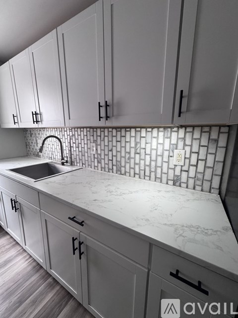 A kitchen with white cabinets and a marble countertop.