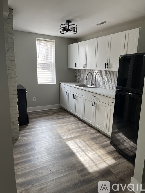 A kitchen with white cabinets and a black refrigerator.
