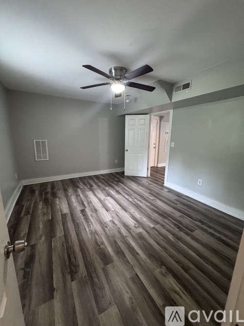 A room with a ceiling fan and wooden flooring.