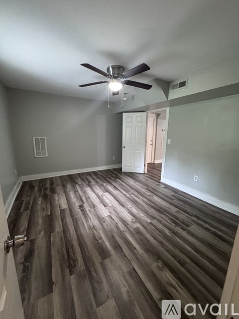 A room with a ceiling fan and wooden flooring.